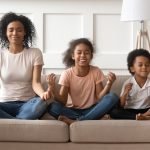 Happy black mother with son and daughter meditating.